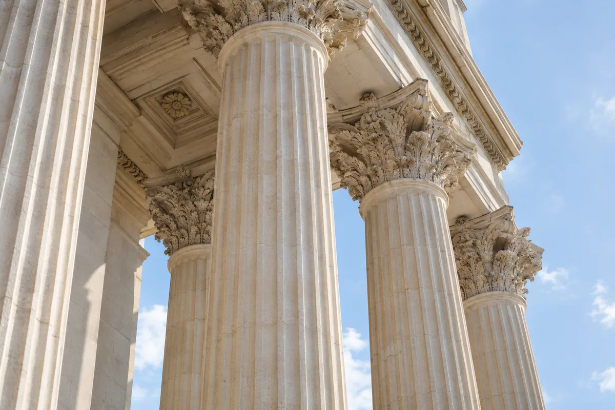 Façade à colonnes d&rsquo;un bâtiment institutionnel en pierre claire vue en contre-plongée sous un ciel pâle